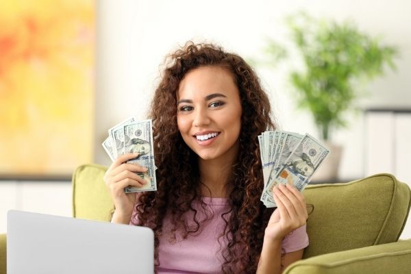Woman sitting at computer holding money